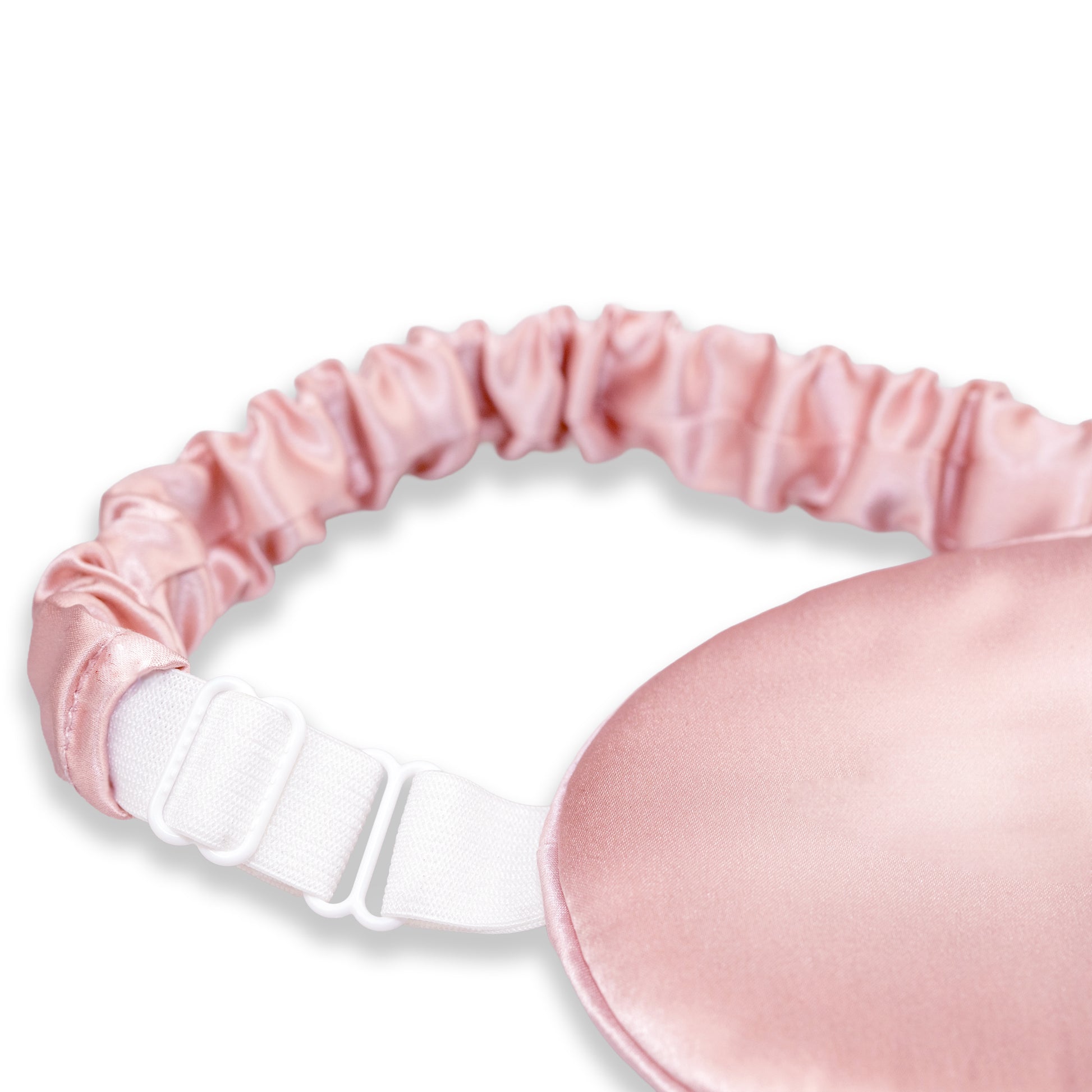 A close-up of a pink SILKAVA silk sleep mask with an adjustable white elastic strap and metal slider buckle