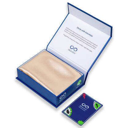SILKAVA silk pillowcase in packaging alongside Origin Series collectible card, champagne
